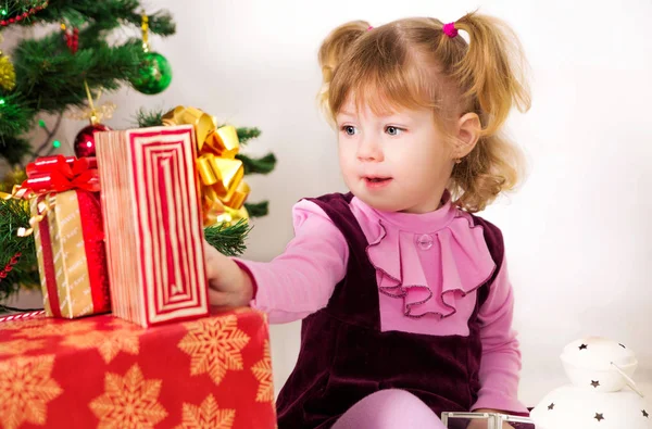 Little girl with Christmas gifts near the Christmas tree Stock Image
