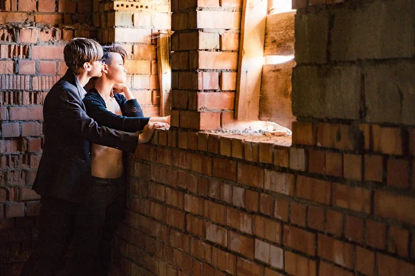 Chico y chica están posando en las paredes de una vieja casa — Foto de Stock