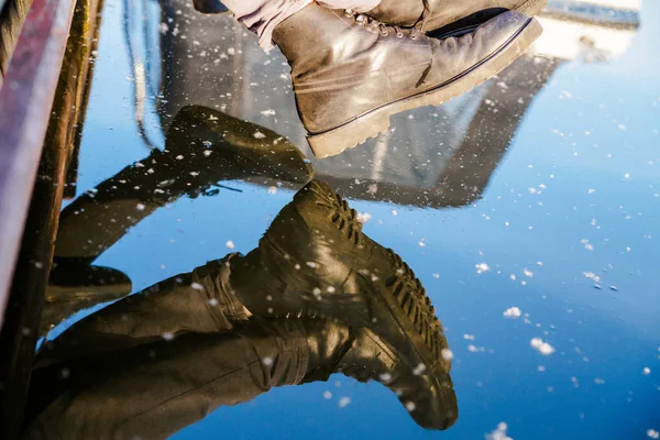 reflection of mens shoes in the water