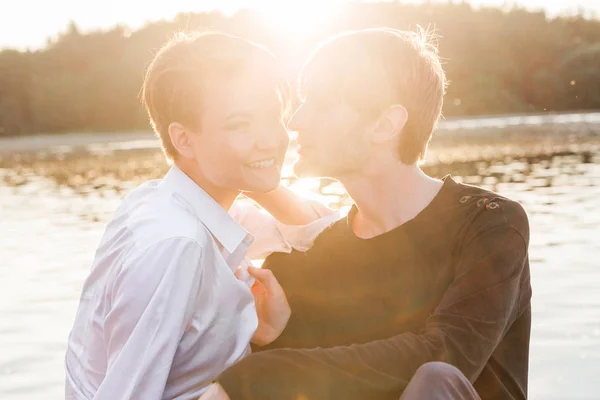 Junge und Mädchen zusammen am See bei Sonnenuntergang — Stockfoto