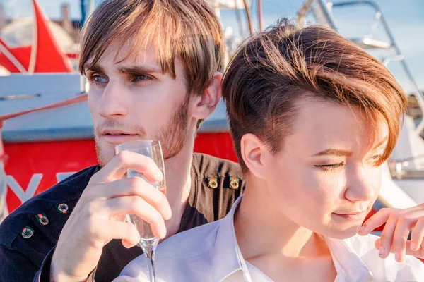 Junge und Mädchen trinken Champagner auf der Anklagebank — Stockfoto