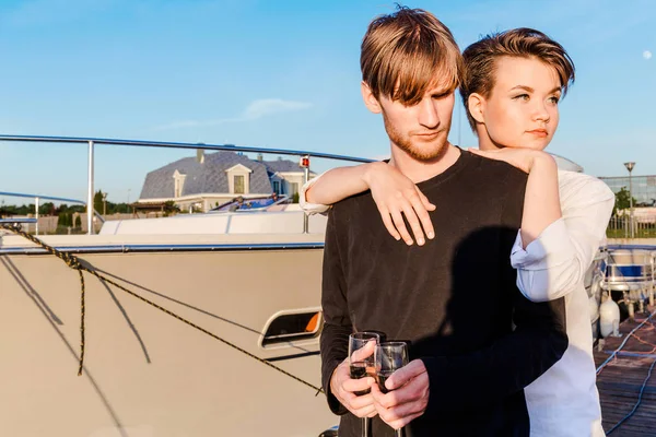 Junge und Mädchen trinken Champagner auf der Anklagebank — Stockfoto