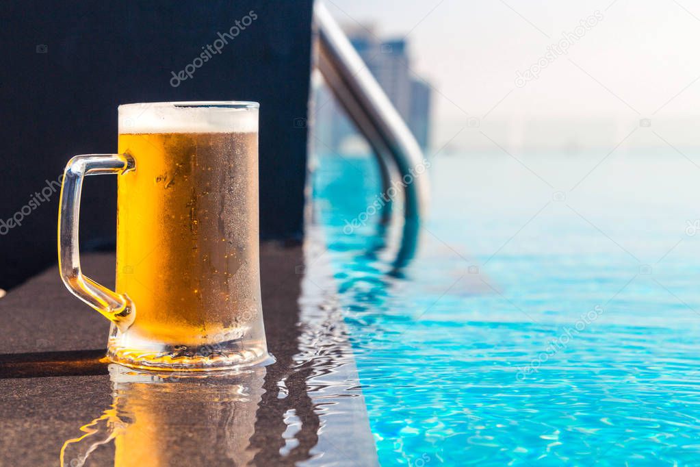 Photo of A glass of beer on a sunny day by the pool
