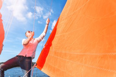 adam yelkenli bir teknede çeker. Yatay fotoğraf