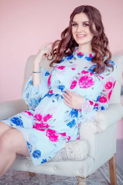 hamile mutlu kadın sandalyede oturuyordu. Pastel pembe odada