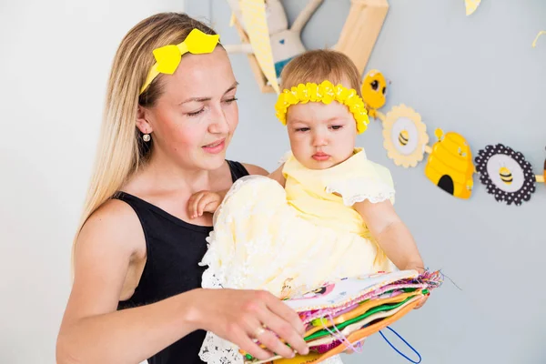 Mamá y su hija están sentadas en el suelo y mirando un libro de fieltro . — Foto de Stock