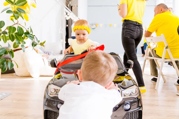 The girl is the driver of the pear machine. Boy pushes car — Stock Photo, Image