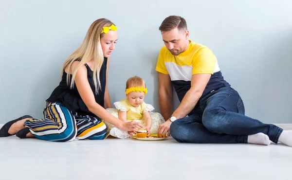 带着一个小女儿的父母坐在地板上吃蛋糕 — 图库照片