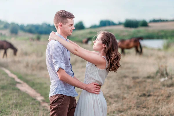 Lovers man and woman together. Horses in the background — Stock Photo, Image