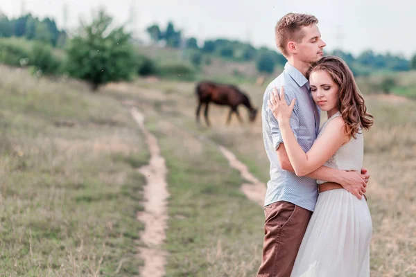Lovers man and woman together. Horses in the background — Stock Photo, Image