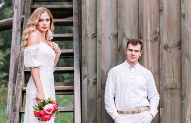 Gelin ve damat bir merdiven ile eski ahşap evin yanında poz