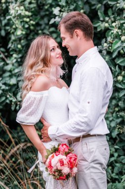 Gelin ve damat ormanın zemine karşı poz peonies bir buket