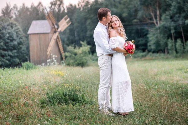 Bruid en bruidegom poseren tegen de achtergrond van een oude houten molen — Stockfoto