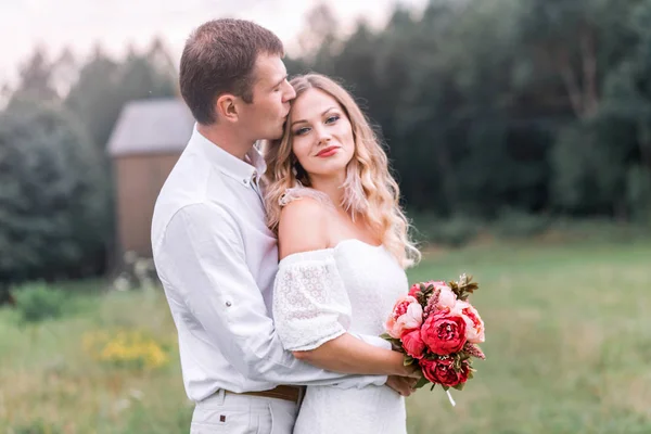 Bride and groom with a bouquet of peonies — Stock Photo, Image