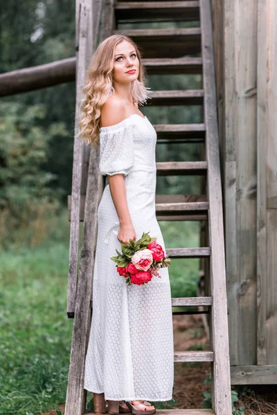 Невеста с букетом пионов на деревянной лестнице — стоковое фото