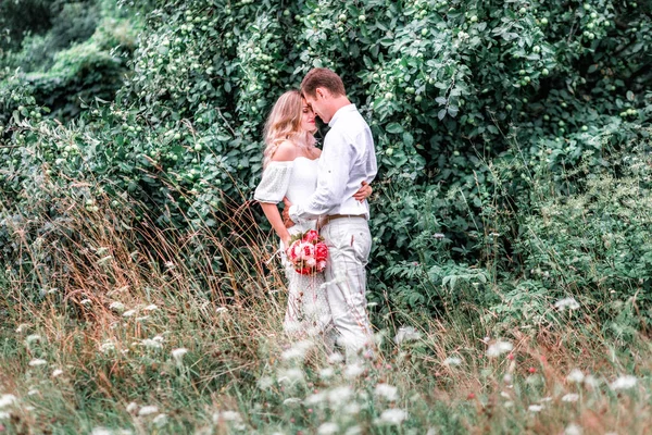 Bride and groom with a bouquet of peonies posing against the backdrop of the forest — Stock Photo, Image