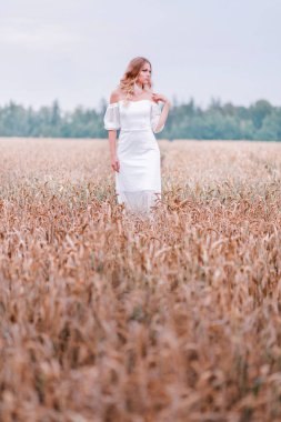 Poz buğday bir arka plan üzerinde beyaz bir elbise içinde gelin