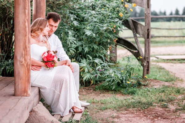 Noiva e noivo estão sentados no limiar de uma casa de madeira — Fotografia de Stock