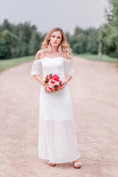 Красивая невеста с букетом цветов на фоне дороги — стоковое фото