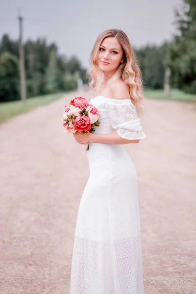 Hermosa novia con un ramo de flores sobre el fondo de la carretera —  Fotos de Stock