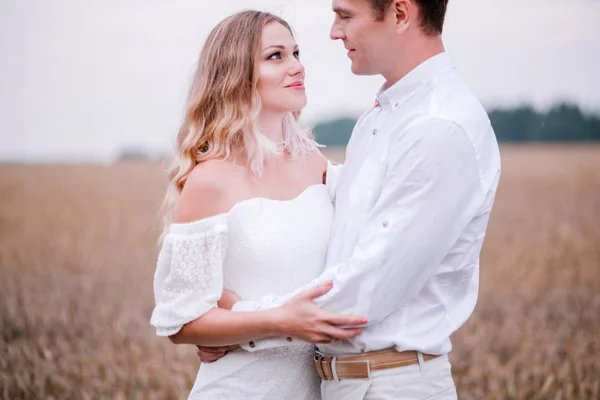 Bride and groom posing against the backdrop of a wheat field — Stock Photo, Image