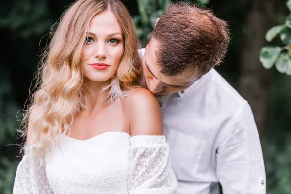 The groom kisses the bride on the bare shoulder — Stock Photo, Image