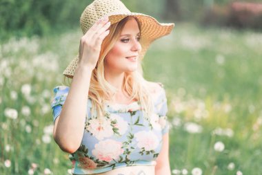 Karahindiba tarlasında arka planda şapkalı bir kadın.