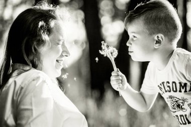 çocukların yüzüne karahindiba üflüyor. Balck ve beyaz