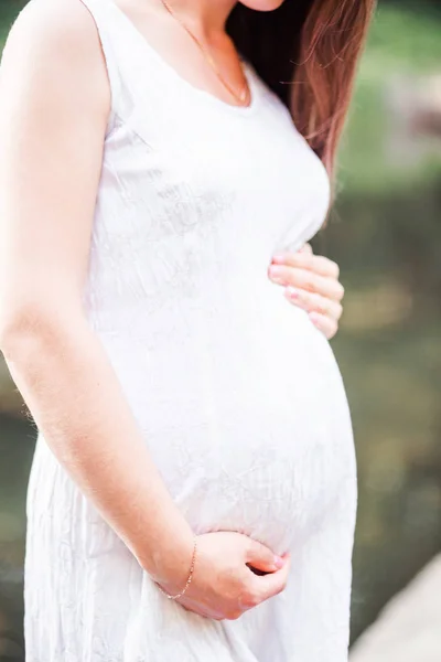 快乐的孕妇在白色礼服拥抱她的肚子 — 图库照片