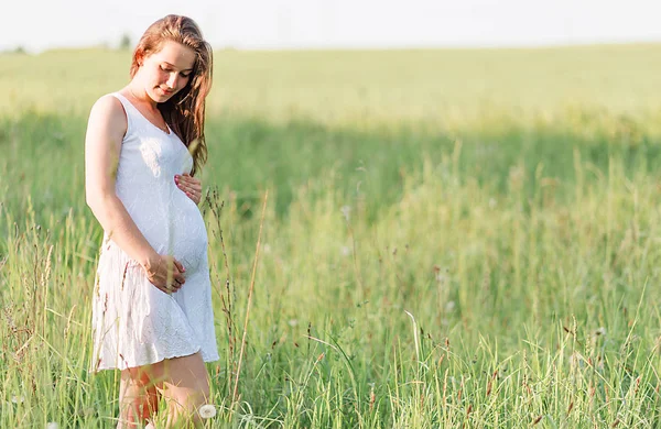 美丽的孕妇在草地上的白色礼服 — 图库照片