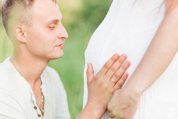 Будущий отец обнимает и целует своих жен беременным животом — стоковое фото