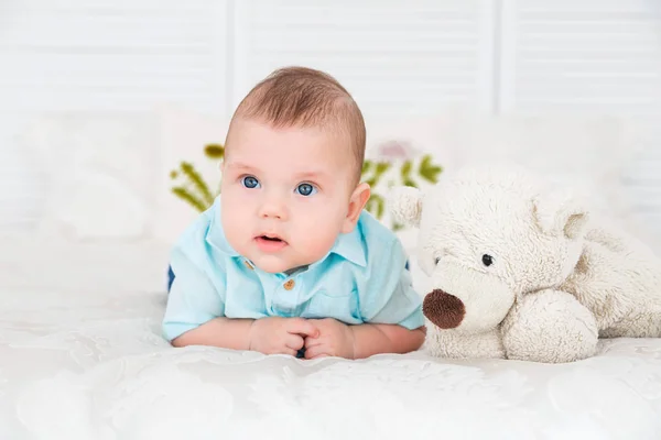 Kleiner Junge liegt auf dem Bett neben einem Teddybär — Stockfoto