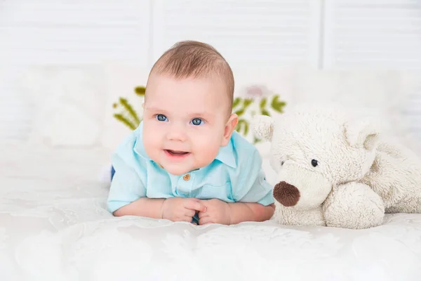 Kleiner Junge liegt auf dem Bett neben einem Teddybär — Stockfoto