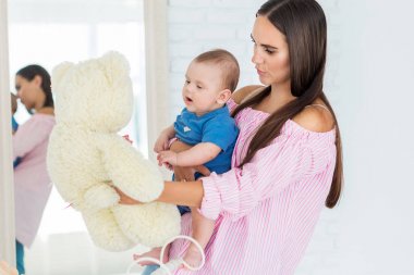 Anne küçük oğluna bir oyuncak ayı gösterir