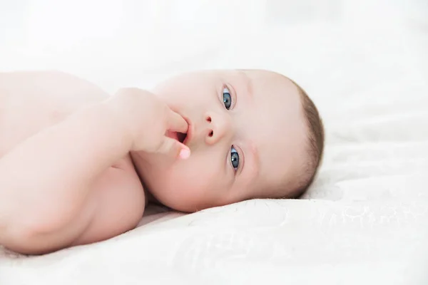 Retrato de un bebé acostado en una cama blanca — Foto de Stock