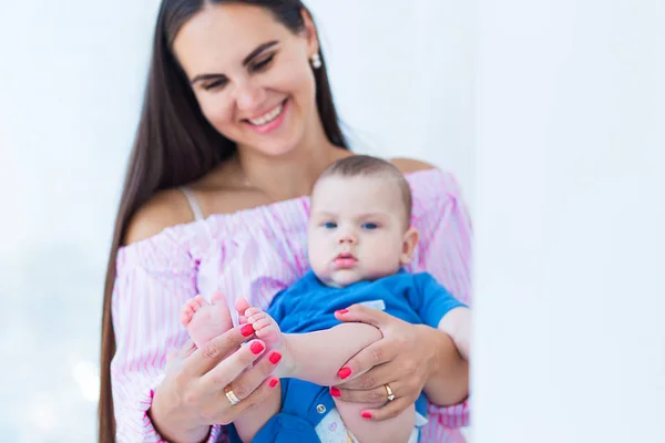 La jeune mère tient les petites jambes de son fils et sourit — Photo