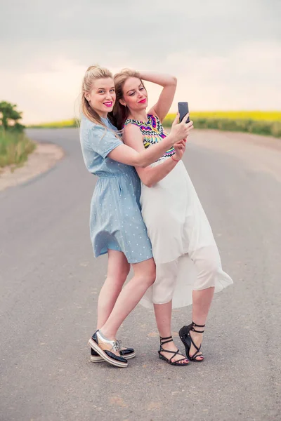 Due ragazze modelli in piedi sulla strada e prendere selfie insieme — Foto Stock