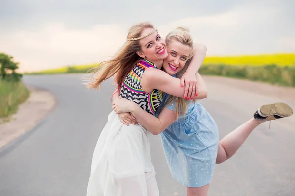 Due ragazze modelli stanno abbracciando, sorridendo e guardando la fotocamera — Foto Stock