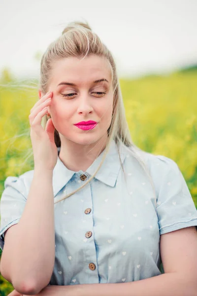 Beautiful girl posing for the camera in the rapeseed field — Stock Photo, Image