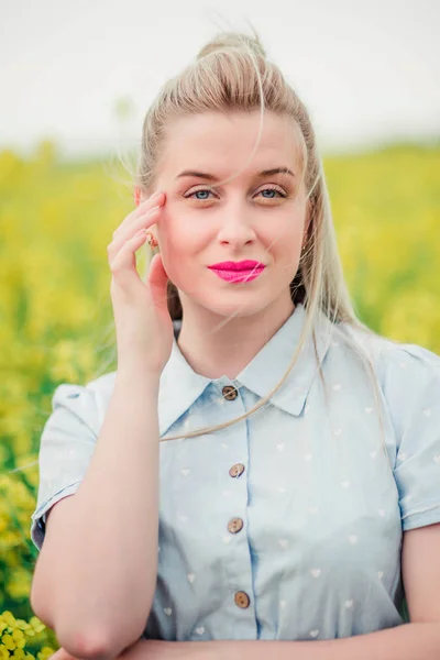 Beautiful girl posing for the camera in the rapeseed field — Stock Photo, Image