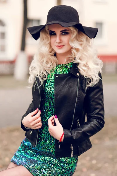 Beautiful blonde girl in a brilliant dress and leather jacket — Stock Photo, Image