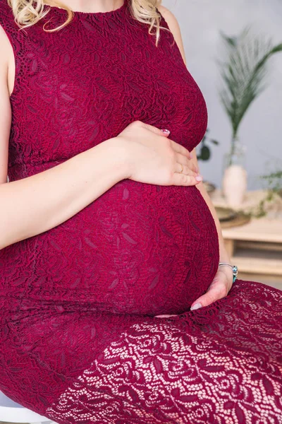 Embarazada chica en burdeos vestido abraza vientre —  Fotos de Stock