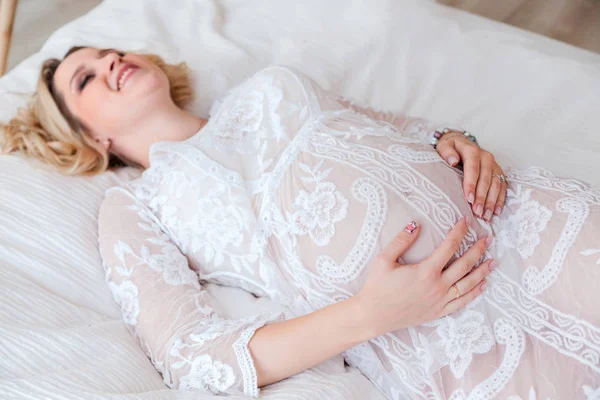 Gelukkige vrouw in witte jurk is liggend op het bed — Stockfoto