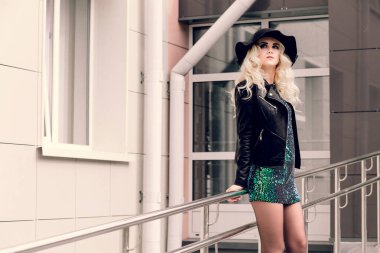 Siyah şapkalı ve deri ceketli kız şehirde yürüyor.