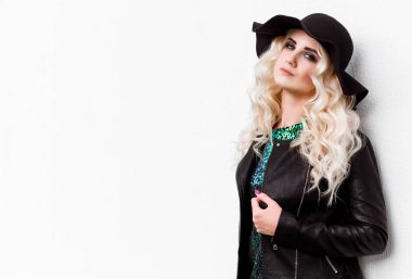 parlak bir elbise ve deri ceket beyaz duvara karşı poz güzel sarışın kız