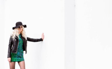 parlak bir elbise ve deri ceket beyaz duvara karşı poz güzel sarışın kız