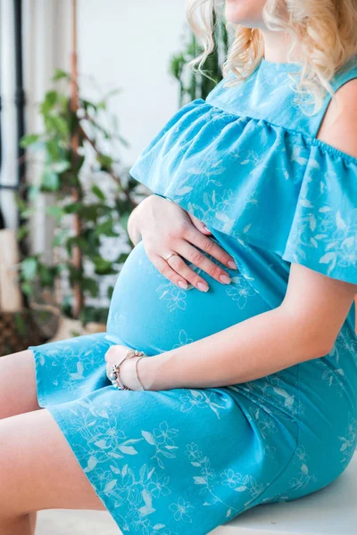 Embarazada en un vestido azul abraza su vientre —  Fotos de Stock