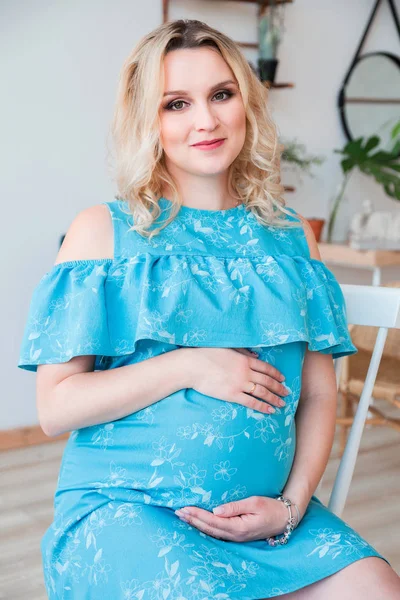 Mulher grávida em um vestido azul abraça sua barriga — Fotografia de Stock