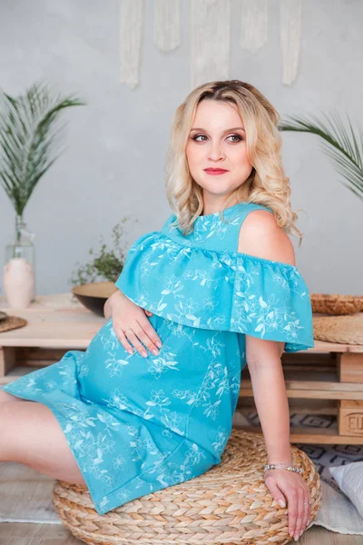 Беременная женщина в синем платье обнимает живот — стоковое фото