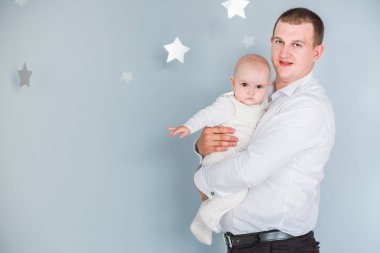 baba kollarında küçük bir oğlu tutar ve mavi bir arka plan üzerinde pozlar